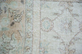 Softened ivory and earth tone allover pattern on distressed vintage Oushak rug.