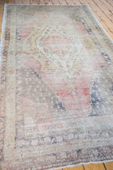 Distressed texture of a Turkish Oushak runner showing faded coral, gold, and navy motifs.
