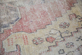 Distressed Oushak runner texture, showing faded red, beige, and dark geometric motifs.