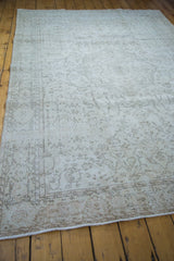 Distressed texture and faint floral patterns on a blanched Oushak carpet field.
