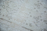 Distressed Oushak carpet showing blanched pile, faint pattern in ivory, beige, charcoal.