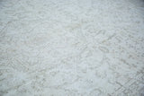 Distressed Oushak carpet pile with faded ivory and faint charcoal patterns.