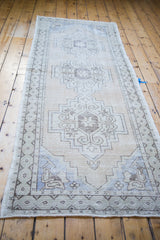 Vintage Oushak runner with distressed texture, showcasing geometric medallions and soft blue accents.