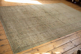 Decorative distressed Oushak rug border showing intricate patterns in blanched green and beige.