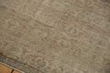 Blanched ivory, green, and beige tones on the distressed corner of Oushak rug.