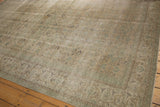 Textured corner of a distressed Oushak carpet with softened ivory, green, and beige hues.