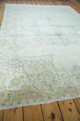 Vintage distressed Oushak carpet with blanched ivory, soft green, and tan texture.