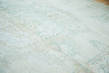 Distressed Oushak carpet with blanched ivory, soft green, and beige curvilinear patterns.