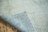 Distressed Oushak rug's blanched ivory texture and muted blue-grey woven foundation.
