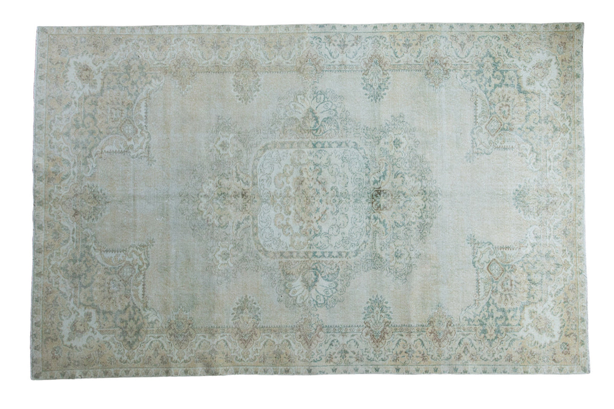 Distressed Oushak carpet featuring a blanched ivory and green medallion, 6' x 9'5".