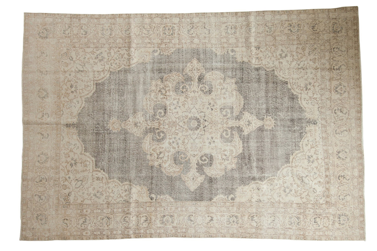 Distressed Oushak carpet features a blanched ivory medallion on a charcoal field, 6'10" x 10'3".