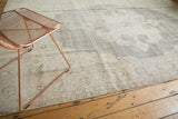 Distressed Oushak carpet with intricate blanched ivory, beige, and charcoal medallion.