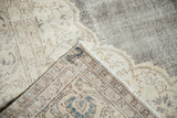 Distressed Oushak rug corner revealing blanched ivory, beige tones and hand-knotted reverse.