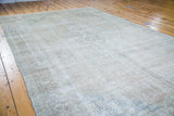 Distressed Oushak carpet texture with muted patterns in soft coral, silver, and tan.