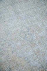 Distressed Oushak carpet featuring worn texture and soft charcoal and tan patterns.