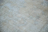 Distressed texture close-up of the Oushak carpet with soft tan, silver, and charcoal colors.