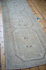 Distressed vintage Oushak rug texture in blanched tones, featuring faded coral and dark motifs.