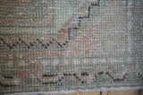Distressed Oushak rug pile texture in blanched beige, coral, and charcoal tones.
