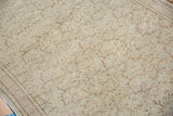 Distressed blanched beige texture with muted brown scrolling vines on the Turkish Oushak rug.