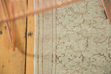 Blanched distressed Turkish Oushak rug with scrolling vine pattern and striped border.