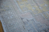 Distressed vintage Oushak rug showcasing muted gold, apricot, and silver geometric patterns.