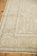 Distressed Oushak rug with faded ivory, soft blue-green, and brown shadow patterns.