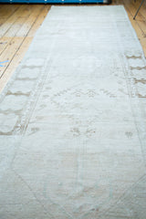 Detailed view of the distressed Oushak rug's worn texture, showcasing soft cream tones and faded geometric patterns.
