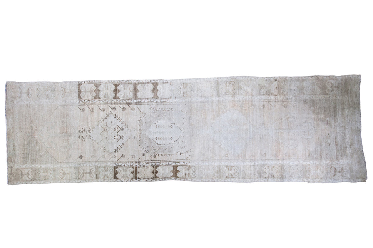 Distressed Oushak rug runner, light beige tone-on-tone geometric motif, worn aesthetic.