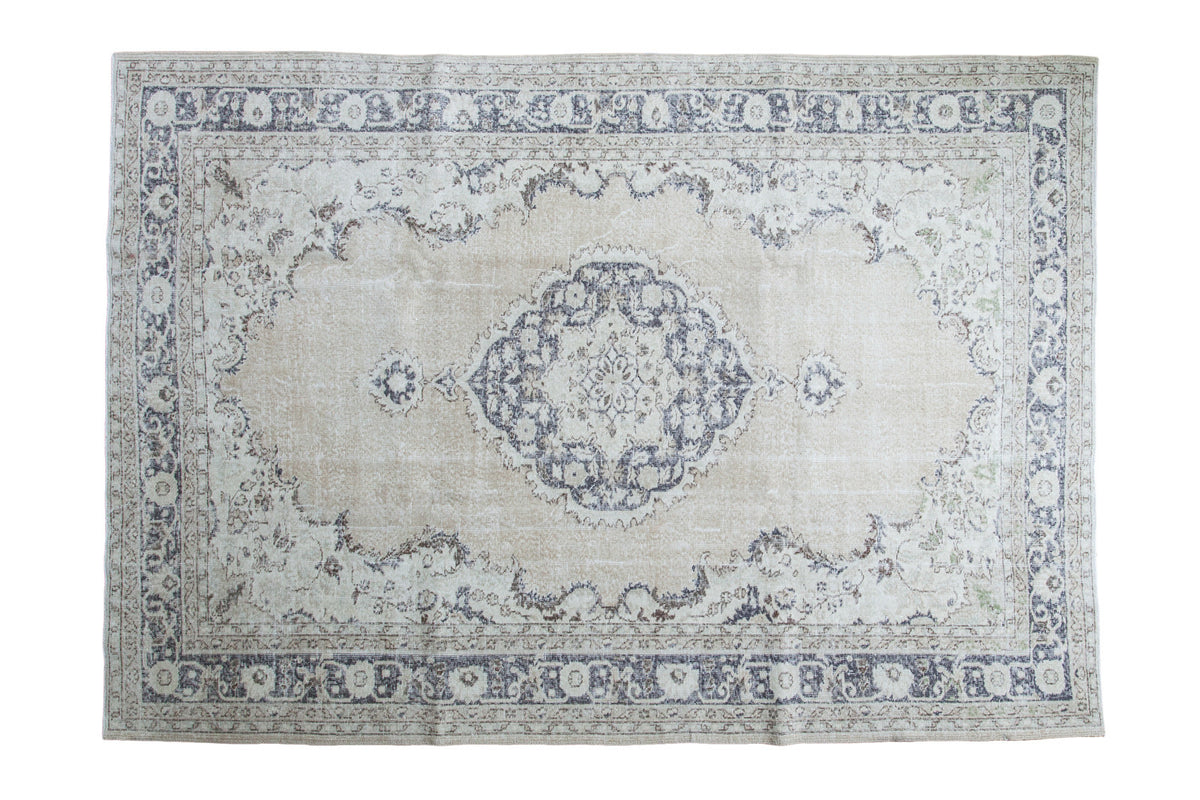 Distressed Turkish Oushak carpet with faded blue medallion on beige field, 7'3" x 10'4".
