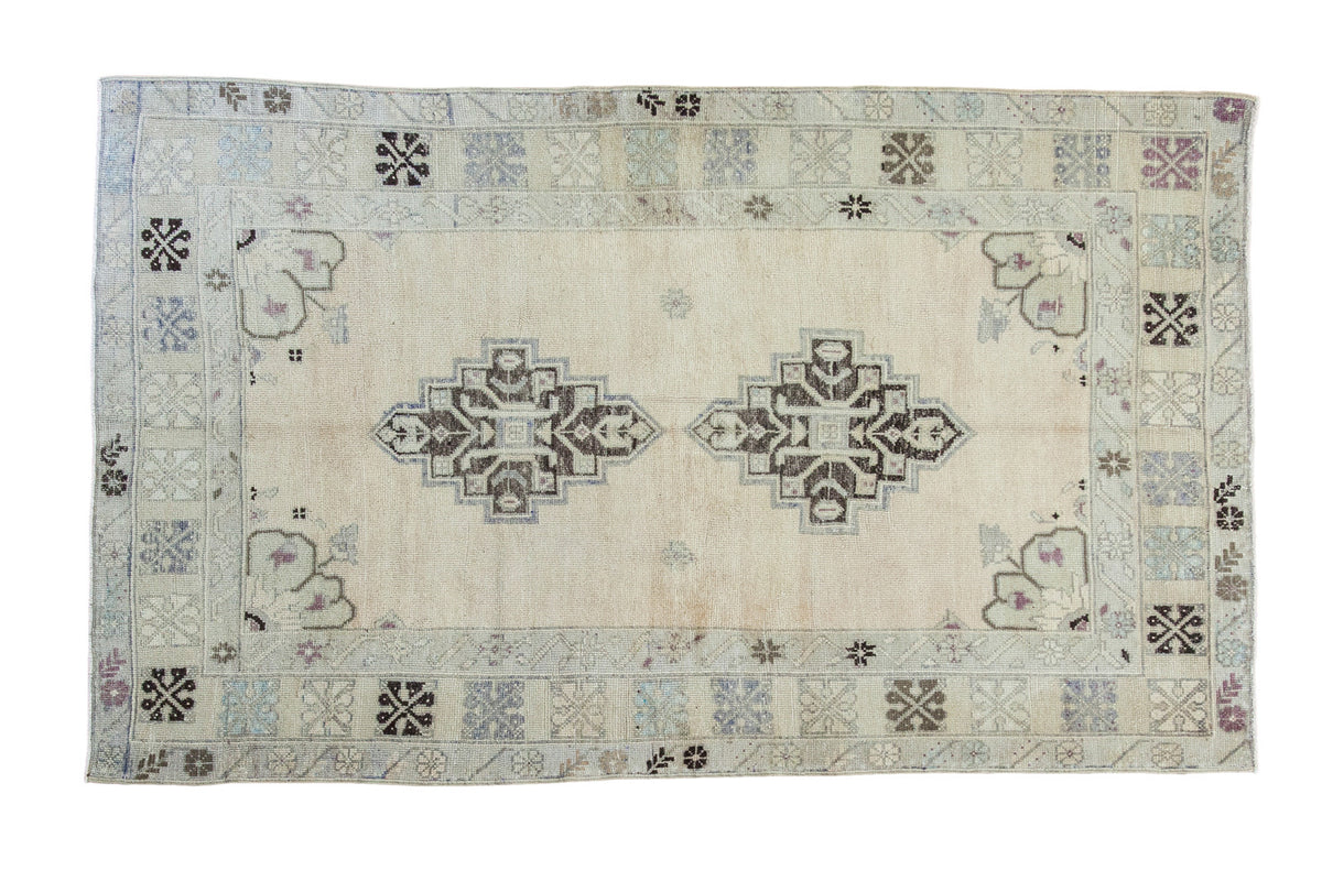 Vintage Turkish Oushak rug, double charcoal medallion, open beige field, geometric ivory, plum.