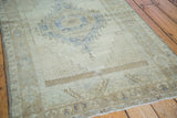 Distressed Oushak rug with faded blue medallion and soft bronze patterned border.