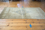 Distressed vintage Turkish Oushak rug with faded silver medallion and golden field.