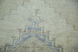 Distressed Oushak rug texture with faded blue and soft bronze curvilinear pattern.