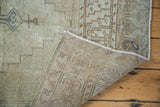 Distressed Oushak rug corner, revealing hand-knotted backing and faded geometric pattern with soft bronzes.