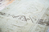 Faded beige field and charcoal geometric motifs on the distressed vintage Oushak rug.