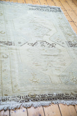 Distressed vintage Oushak rug, showing muted beige field, silver, bronze, and charcoal accents.
