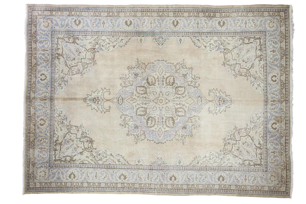 Vintage Oushak carpet with large central medallion, open field, soft tan, silver-blue tones.