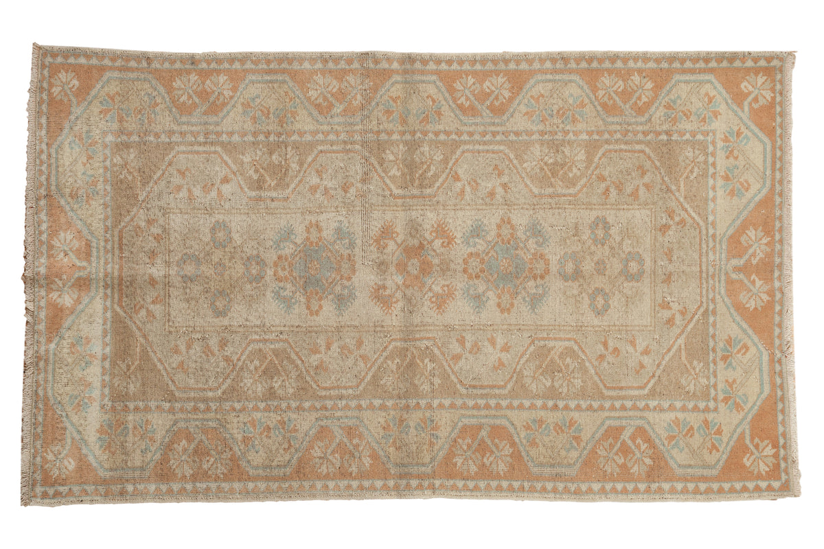 Decorative distressed Oushak rug with blanched, sandy beige, soft blue, and terra cotta geometric motifs.