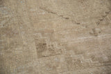 Worn pile texture with soft sandy earth tones and distressed patina.