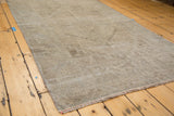 Distressed Oushak rug edge, highlighting worn texture and subtle sandy earth tones.