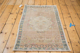 Upper section of a distressed vintage Oushak rug, with blanched medallion and soft pastels.