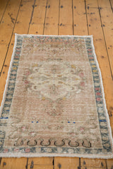 Vintage Oushak rug's angled view, highlighting distressed texture and faded pastel tones.