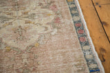 Blanched earth tones and distressed texture on a vintage Oushak rug's geometric border.