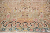 Blanched pastel and earth tone motifs with distressed texture on a vintage Oushak rug.