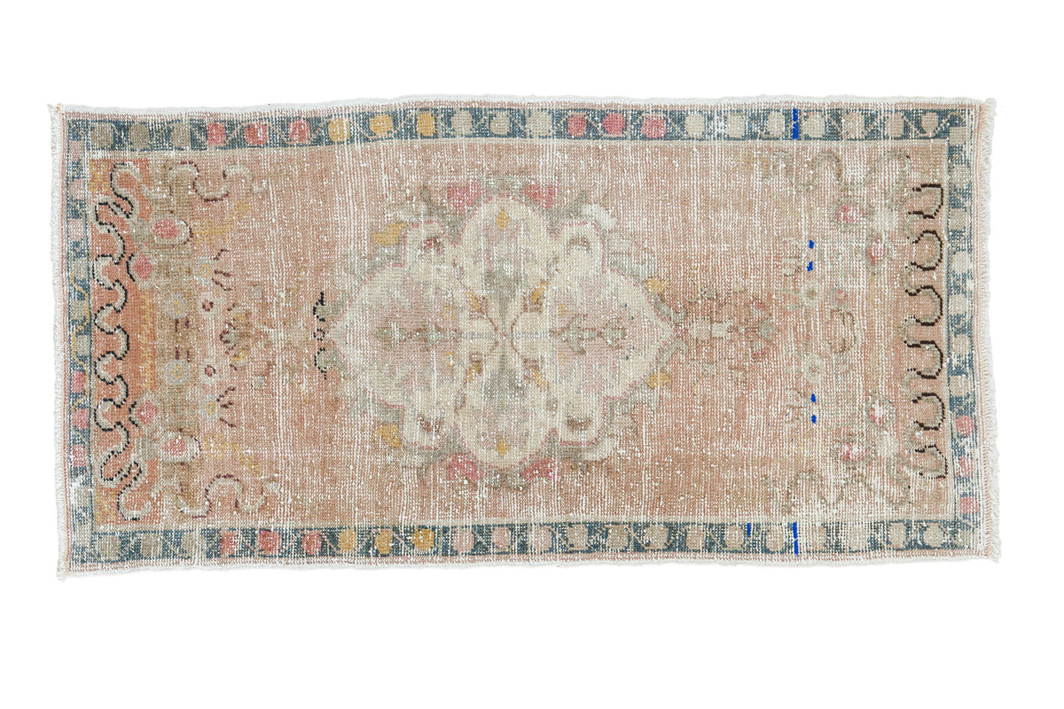 Distressed vintage Oushak rug with large medallion, soft earth tones, and blanched pastels.