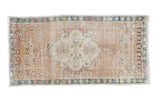 Distressed vintage Oushak rug with large medallion, soft earth tones, and blanched pastels.