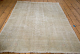 Distressed vintage Oushak rug with faded ivory, grey, and subtle rose tones.