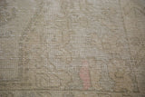 Distressed Oushak rug showing blanched ivory, grey, and soft rose textured pile.