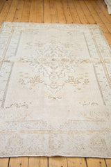 Faded curvilinear medallion and lotus motifs on a distressed Oushak rug.