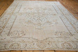 Distressed Oushak rug with oversized lotus flower border, scalloped contours, and soft earth tones.